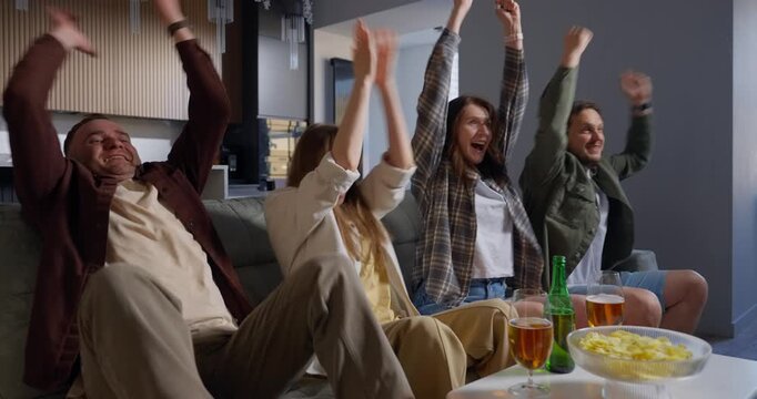 A group of four friends sitting on a couch in a cozy modern living room, watching an exciting event on TV with intense focus and enthusiasm, sharing drinks and snacks together