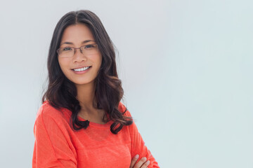 Fototapeta premium Asian woman standing facing camera in studio, wearing orange long-sleeve top and clear glasses