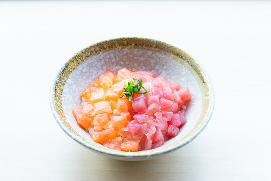Delicious Japanese Bara Chirashi Don featuring diced raw salmon and tuna sashimi over rice in a ceramic bowl on white background.