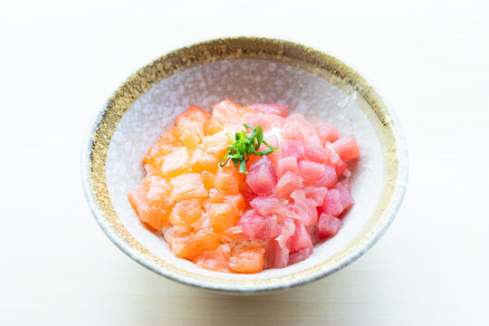 Delicious Japanese Bara Chirashi Don featuring diced raw salmon and tuna sashimi over rice in a ceramic bowl on white background.