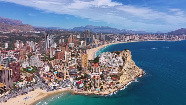 Benidorm coastline Spain showing skyscrapers hotels curved sandy beach turquoise Mediterranean sea rocky headland mountains in background sunny summer day