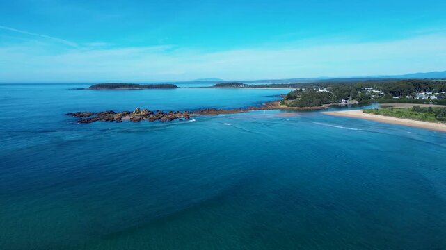Drone aerial landscape of clear ocean waves breaking on shoreline at beach with rocky reef headland coastline of Mossy Point town near Broulee and Tomakin South Coast NSW Australia tourism and nature