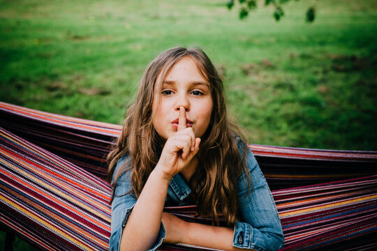 Portrait of girl in hammock with finger on her mouth