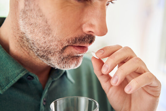 Close-up of adult man taking pill
