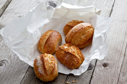 Five bread rolls on paper and grey wood