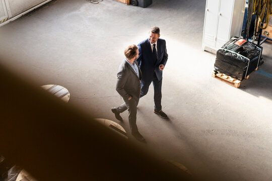 Bird's eye view of two businessmen walking and talking in a factory