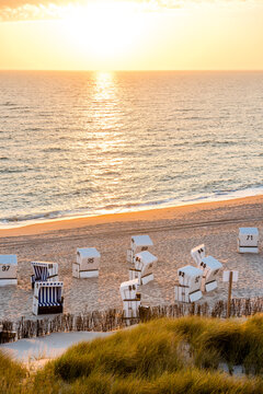 Germany, Schleswig-Holstein, Sylt, beach and empty hooded beach chairs at sunset