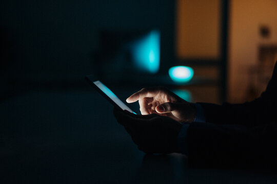 Close-up of businessman working late in office using tablet