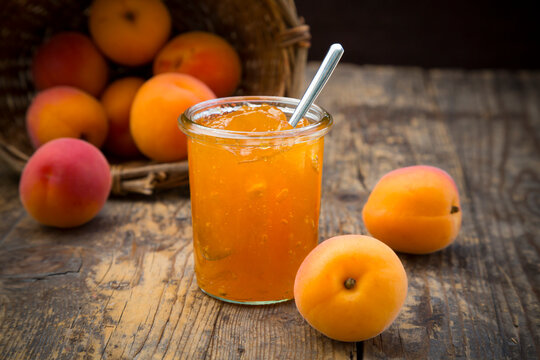 Glass of apricots jam and apricots on wood