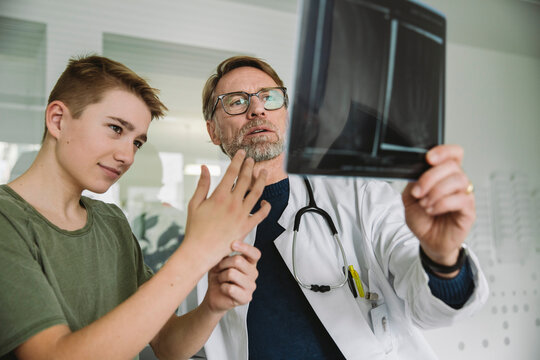 Doctor explaining to teenage boy in medical practice