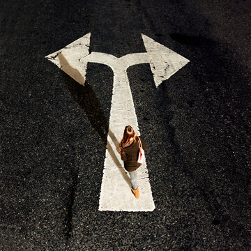 Woman walking on directional arrow of a road