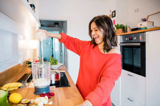 Woman prearing fruit smoothie in her kitchen