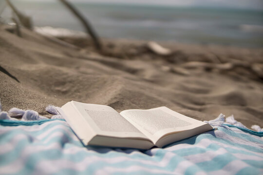 Italy, Tuscany, Maremma, book on beach towel