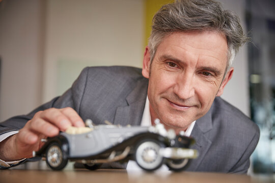 Mature man playing with classic car model