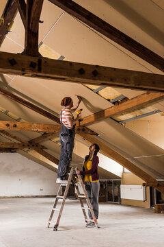 Young man and woman mouting insulation on construction site
