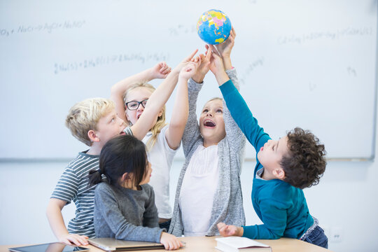 Ecstatic students unite to hold the world in their hands during a classroom lesson