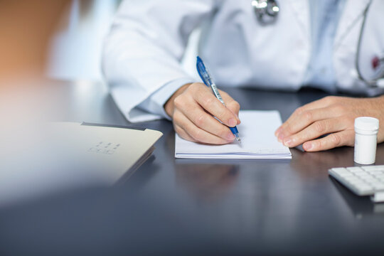 Doctor sitting at his desk taking notes