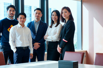 Fototapeta premium Portrait of Asian young adult business team standing in office, facing camera and presenting professional leadership and collaboration. Ideal for corporate branding, recruitment