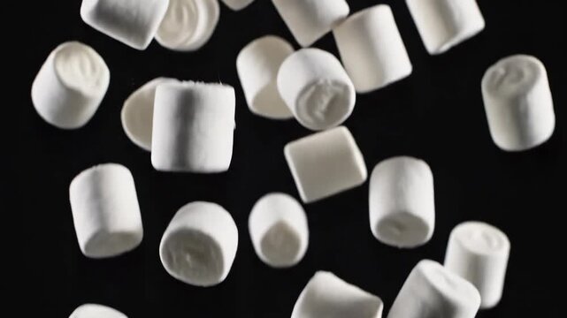 Delicious fluffy white marshmallows falling against a dark background, perfect for sweet treats and desserts.