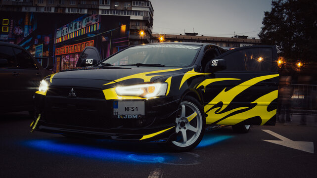 Kyiv, Ukraine - October 20, 2023. A custom car with yellow flame graphics and underglow lighting was displayed at Kyiv Car Fest, an automotive exhibition featuring modified, tuned, and show vehicles.
