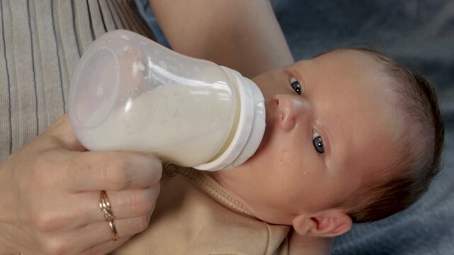 Newborn baby drinking milk from a bottle