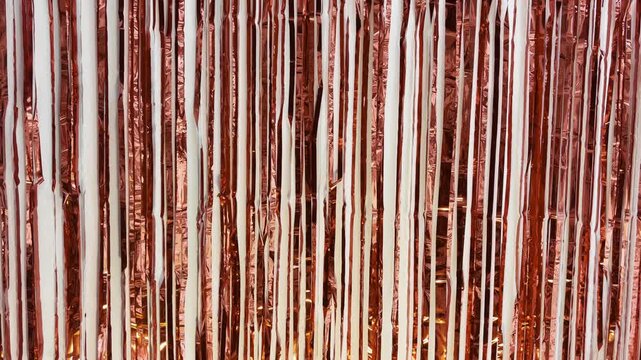 Shimmering red gold fringe tinsel curtain fluttering against a clean white background. Glamorous metallic foil streamers creating a sparkling, festive texture for any celebration or event