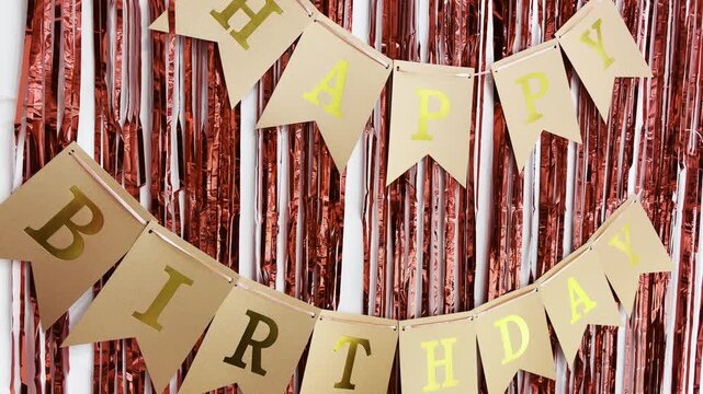 Festive happy birthday bunting with shimmering rose gold tinsel curtain for party decoration. Fun celebration backdrop for special event, anniversary, or holiday greeting