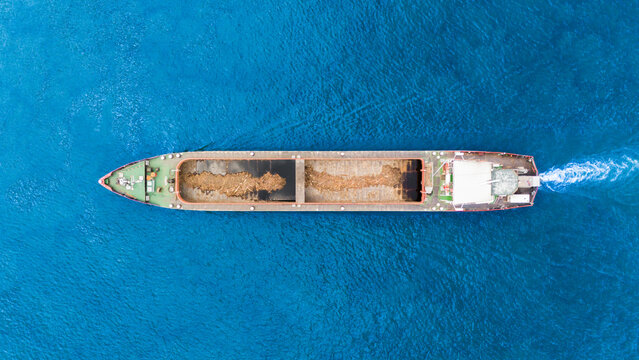 Aerial view of a large cargo barge transporting bulk materials across the deep blue waters of the Danube river in Novi Sad, Vojvodina, Serbia.