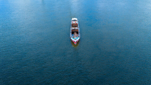 Aerial view of a cargo barge navigating the blue waters of the Danube river with gentle ripples Novi Sad, Vojvodina, Serbia.