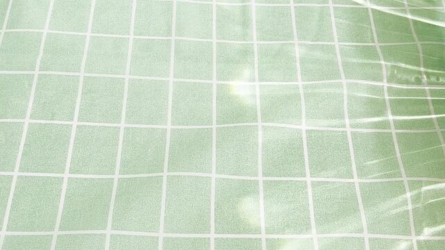 Light green grid pattern with moving caustics creating a mesmerizing background, a soothing and abstract visual loop capturing reflections and shadows in a subtle play of light