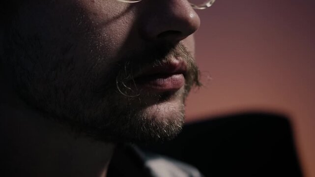 Extreme close up of man biting pizza slice while watching television at night. Shallow depth of field and cinematic low light emphasize food texture and cozy home atmosphere