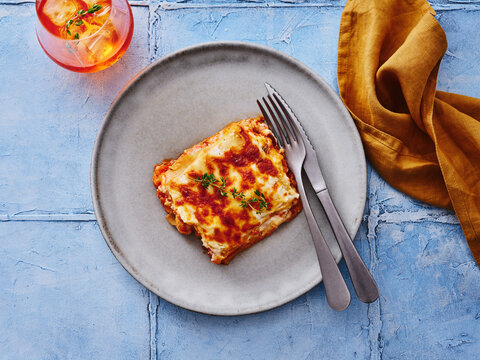 The image showcases a serving of lasagna topped with cheese and fresh herbs on a plate. This versatile dish is ideal for restaurant menus, promotional materials, or food delivery services