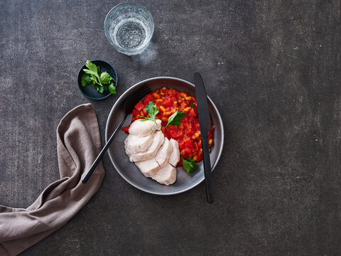 This dish features sliced chicken breast served over a colorful vegetable stew with fresh herbs. Ideal for meal prep, healthy lunch menus, or advertising for restaurants promoting nutritious options