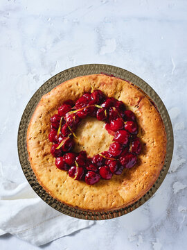 This image features a cherry cake topped with a glossy cherry glaze arranged in a circular pattern