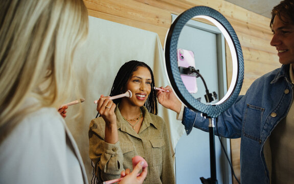 Group creating beauty content with makeup tools and studio lighting equipment
