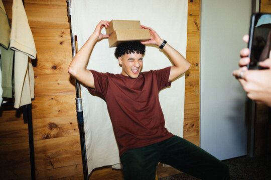 Young influencer playfully posing with a box in a cozy wooden setting