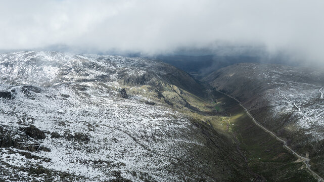 Aerial view of Glacial Valley of Zezere with snow-dusted rocky slopes and low-hanging clouds in Manteigas, Guarda District, Portugal.