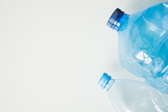 Blue empty plastic bottles on white background with copy space close up. Ecological issues, plastic waste, returning bottles, recycle and reuse