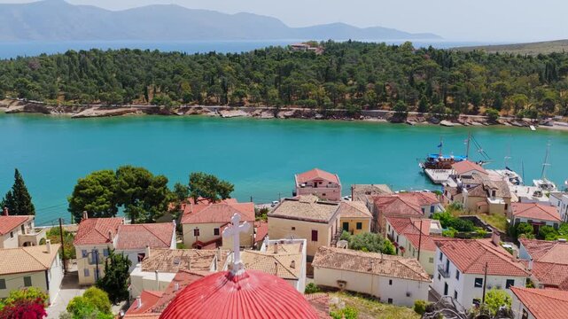 Aerial footage moving away from the church of Saint Nicholas and the picturesque seaside town of Galaxidi, revealing the beautiful turquoise bay and the lush green coastline of Central Greece