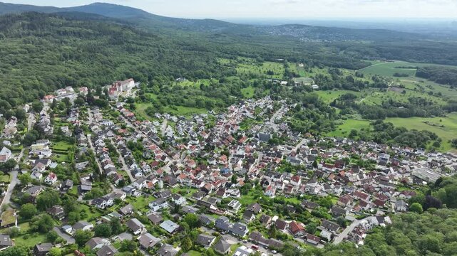 Drone aerial view of Kelkheim-Ruppertshain in the Main-Taunus district of Hesse, Germany, surrounded by dense forests and the rolling hills of the Taunus mountain range under dramatic cloudy skies