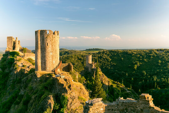 Four Lastours castle ruins standing on rocky ridges above a green forest landscape for historical exploration and cultural tourism in Languedoc-Roussillon, France.