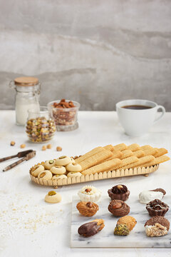 elegant Eid holiday sweets assortment, featuring decorated petits fours, traditional butter biscuits, and Ghorayeba cookies with pistachios, beautifully styled on marble and golden trays with coffee.