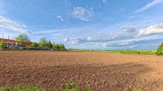 Expansive plowed field under a beautiful blue sky with white clouds on a sunny day