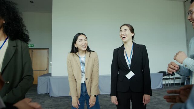 Attendees at a business conference stand together in a circle, smiling and laughing during an informal networking session. They are connecting, discussing, and enjoying each other's company.