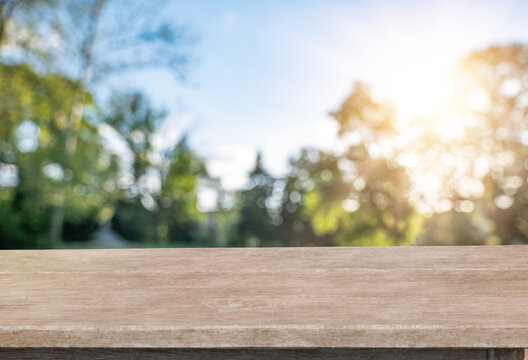 Wooden table product display with blurred natural background and sunlight