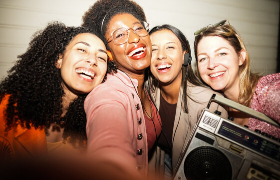 Crazy women friends having fun doing selfie at night time outdoor - Party, nightlife and people lifestyle concept - UGC flash wide lens content - Main focus on center right girl