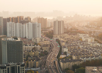 Obraz premium Aerial view captures elevated expressway busy with cars traversing a vast Asian metropolis under a warm, hazy morning sky