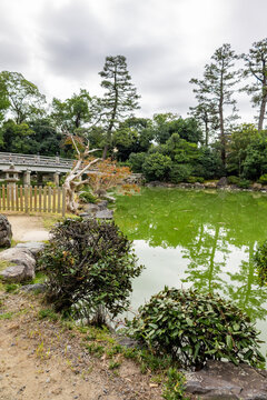 Calm water surface with stones and classic architecture in historic landscaped garden environment, Kyoto, Japan 