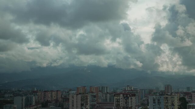 Panning view of storm clouds are scudding over a city at the foot of the Caucasus Mountains timelapse. Storm warning, climate change, environmental protection. Problem of urban air pollution