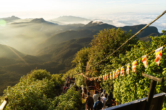 View of Adam's Peak with pilgrims climbing the steep path decorated with Buddhist flags at sunrise Ratnapura, Sabaragamuwa Province, Sri Lanka.